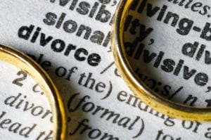 Close up of the word 'divorce' in a dictionary, and two wedding rings on the page