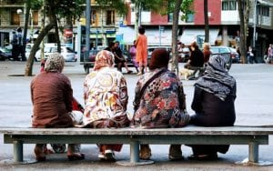 four muslim women sitting on a bench