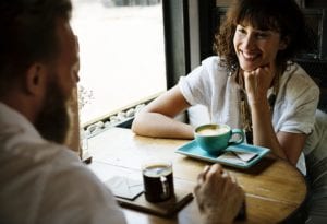 A man and woman drinking coffee and smiling at a table