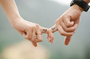 Couple holding hands with anchor tattoos on fingers