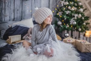 Child laying in front of Christmas tree