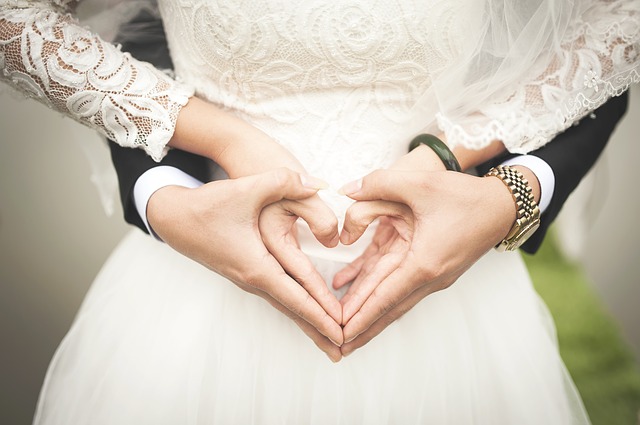 Bride and groom making a heart sign with their hands.
