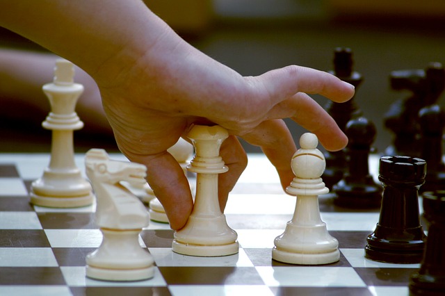 a child's hand moving a chess piece on a board.