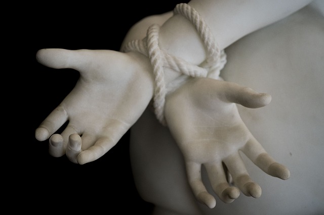 A close up of a statue with tied hands, signifying a kidnapping victim who is being held captive.