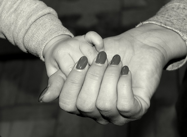 A close up black and white picture of a woman's hand holding a little child's hand.