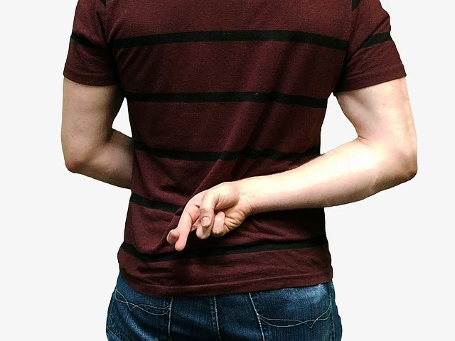 A man holding crossed fingers behind his back, showing that he is being dishonest.