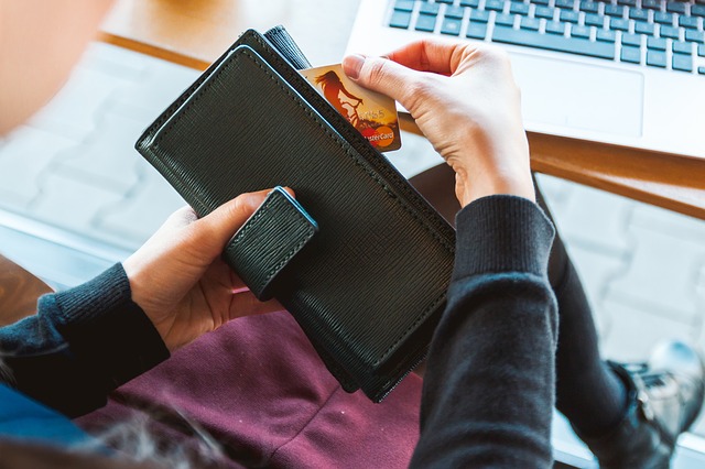 A cpicture of a woman removing a credit card from her wallet.