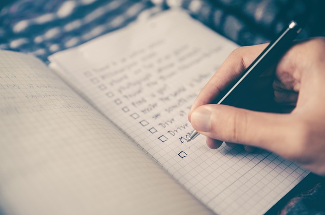 A close up of a person's hand, checking duties off on a list.