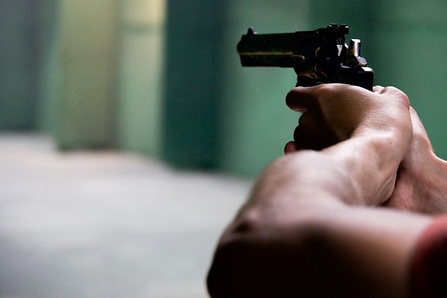 A close up of a man's hands as he holds and points a hand gun.