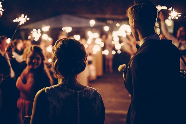 A group of people at a wedding reception. It's dark and the crowd is holding sparklers.