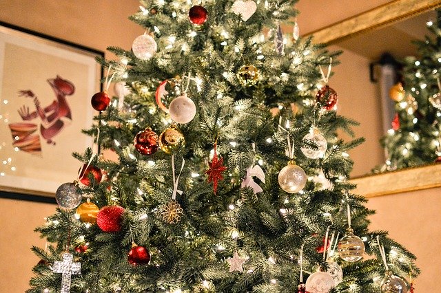 A close up of a Christmas tree, covered with lights and decorated with sparkly decorations.