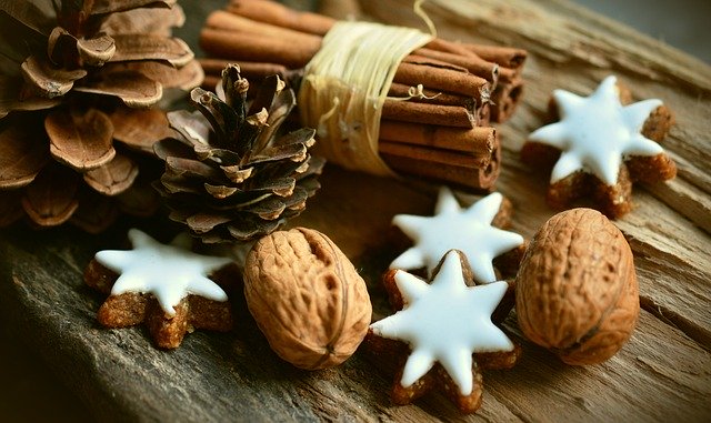 A close up of ginger bread stars, a bundle of cinnamon, and a couple of pine cones