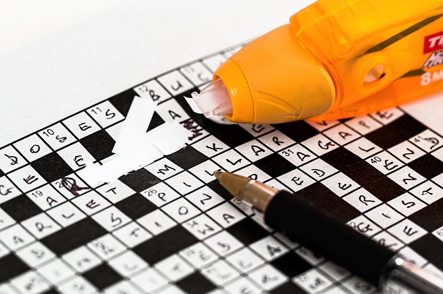 A close up of a crossword puzzle where someone has written the answers in pen, and then used white-out to correct their mistakes.