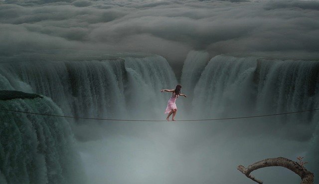 A woman walking across a huge gulf on a tight rope, with huge waterfalls in the background.