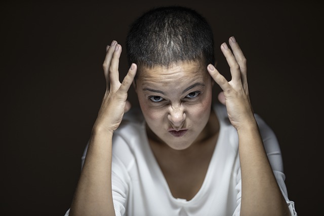 An angry woman, looking at the camera with her hands up and rage on her face.