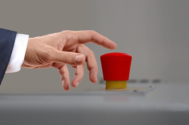 A hand reaching for a red button, as if to press it. The button looks like it is set to activate nuclear war.