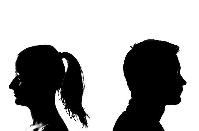 A black and white silhouette of a man and a woman, looking unhappy, with their backs turned to each other