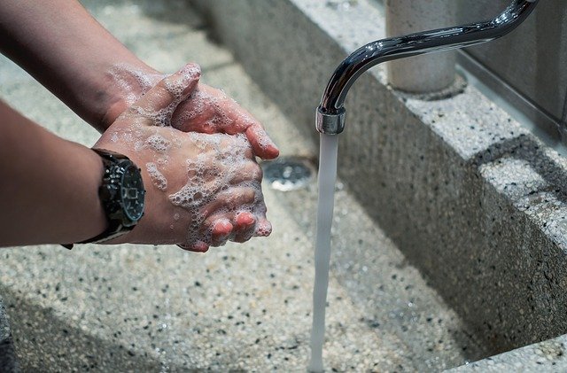 A picture of a person washing their hands well at a sink with soap and water.