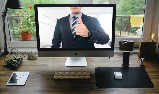 A man appearing on a computer screen in a suit, showing what an online video conferencing meeting with an attorney might look like.