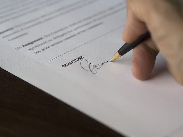 A close up picture of a hand signing a document.