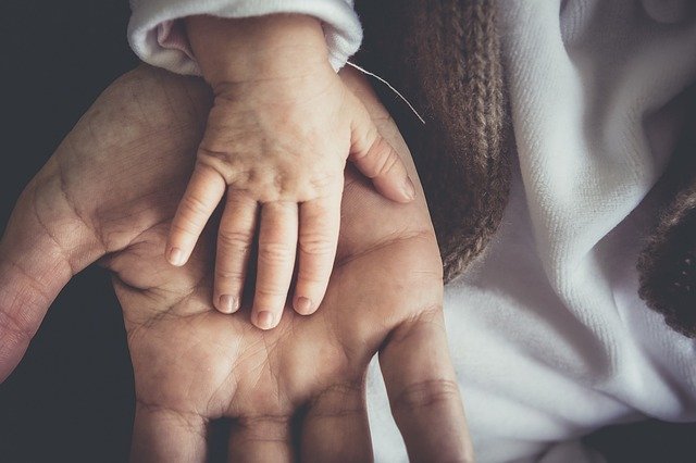 A father's open hand with a small child's hand lying across his palm.