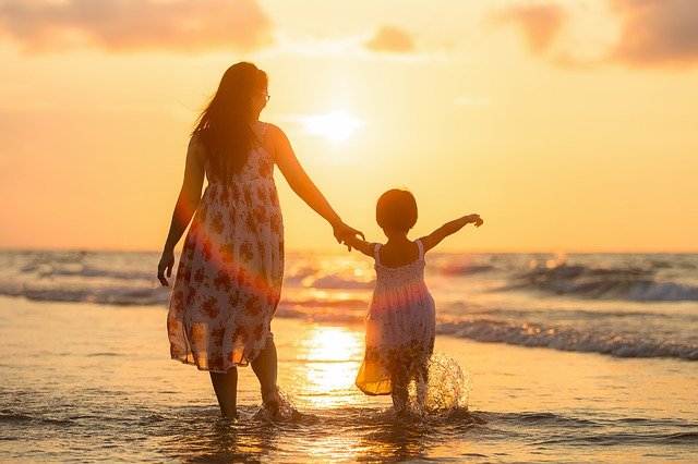 A mother and child walking in the waves towards the sunset. Custody concerns can make parenting very difficult after a divorce.