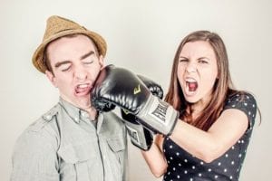 A woman wearing boxing gloves, punching a man in the face