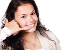 A young woman making a phone symbol withher hand by her ear