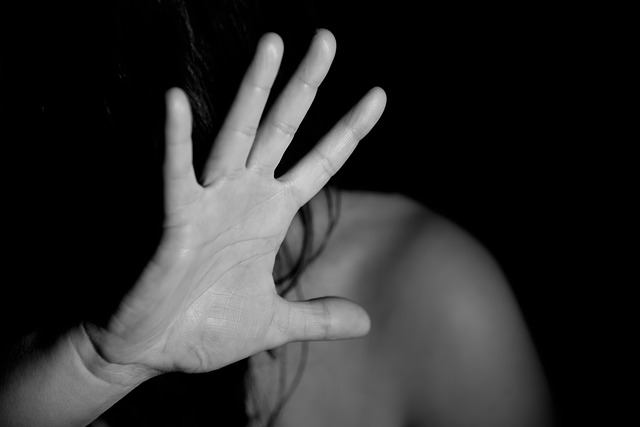 A woman holding her hand up to sheild her face from an attack