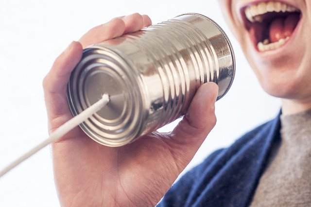 A man speaking into a can with a string coming out of it - symbolizing communication attempts between people