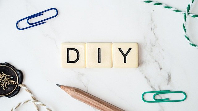 3 Scrabble tiles spelling out "DIY" surrounded by a pencil and paperclips and a wax stamp.