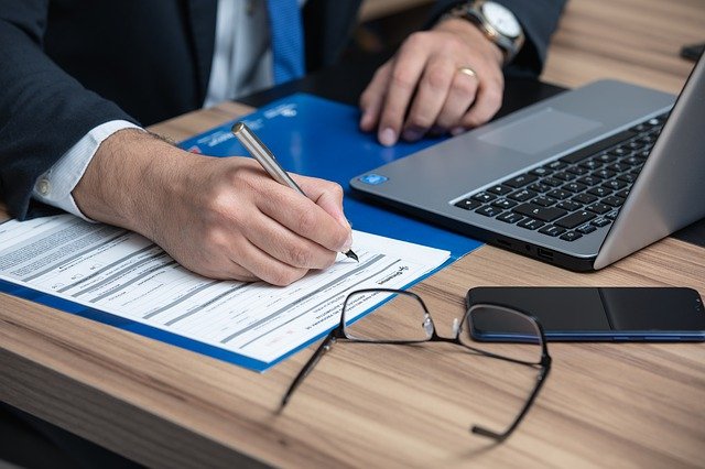 An attorney's hands, as he takes notes on his client's case during an initial consultation.