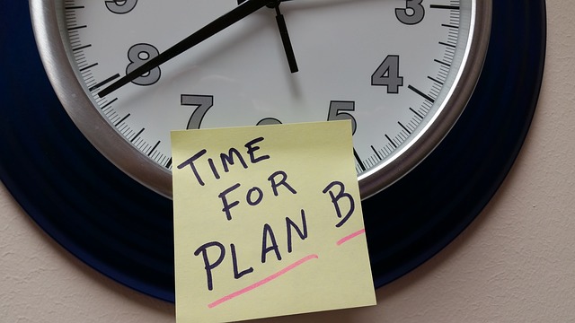 A clock with a post it note stuck to it, saying "Time for Plan B"